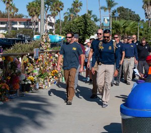 FBI agents walk past a memorial for the victims of the Conception dive boat on the Santa Barbara Harbor, as authorities issue a search warrant for the Truth Aquatics' offices in Santa Barbara, Calif.