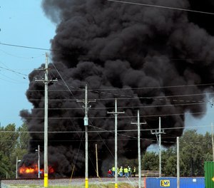 Union Pacific workers and firefighters stage at the scene of a tanker fire from a derailed train near downtown Dupo, Ill. Black smoke coming from the derailment scene can be seen for miles and caused the evacuation of schools in the town, authorities said.