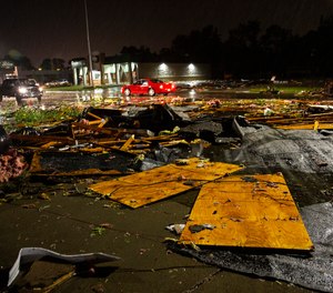 Vehicles drive past debris littering a street after severe weather swept through the area in Sioux Falls, S.D.