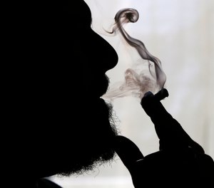 In this Nov. 21, 2014 file photo, a man smokes medical marijuana at his home in Belfast, Maine. Sniff and search is no longer the default for police in some of the 33 states that have legalized marijuana. Traditionally, an officer could use the merest whiff of weed to justify a warrantless vehicle search, and whatever turned up could be used as evidence in court.