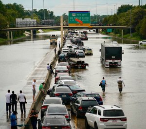People wait outside of their stranded vehicles along Interstate 10 westbound at T.C Jester. The freeway is closed because of high water east bound on the freeway. (Photo/Mark Mulligan, Houston Chronicle via AP)