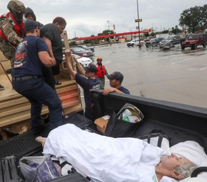 Dwain Kaufman, right, waits for his wife as she is helped into the back of a family member's truck by Beaumont firefighters and members of the Texas National Guard. (Photo/Jon Shapley, Houston Chronicle via AP)