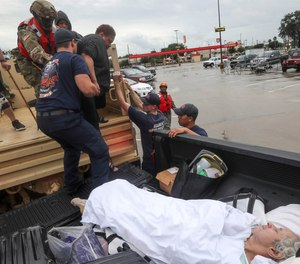 Dwain Kaufman, right, waits for his wife as she is helped into the back of a family member's truck by Beaumont firefighters and members of the Texas National Guard on Thursday, Sept. 19, 2019, in Beaumont, Texas.