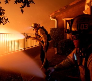 In this Thursday, Oct. 10, 2019 photo, Los Angeles City firefighters battle the Saddleridge fire near homes in Sylmar, Calif. (AP Photo/Michael Owen Baker)