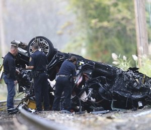 Emergency personnel survey the remains of a Porsche SUV that plummeted off an overpass onto train tracks below Sunday afternoon, where it burst into flames, killing two teenagers and sending a third to a hospital with serious injuries. (Kevin Wexler/NorthJersey.com via AP)
