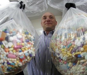 Narcotics detective Ben Hill, with the Barberton Police Department, shows two bags of medications that are are stored in their headquarters and slated for destruction in Barberton, Ohio. (AP Photo/Keith Srakocic)