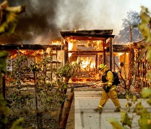 Woodbridge firefighter Joe Zurilgen passes a burning home as the Kincade Fire rages in Healdsburg, Calif.