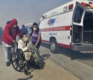 Elderly residents of the Riverside Heights Healthcare Center in Jurupa Valley, Calif., are evacuated from their care facility as flames and smoke from the Hill Fire approach. (Will Lester/The Orange County Register via AP)