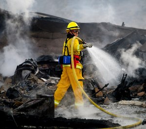 A firefighter sprays water on a leveled home as the Hillside Fire burns in San Bernardino, Calif., on Thursday, Oct. 31, 2019. Whipped by strong wind, the blaze destroyed multiple residences.