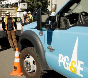 In this Oct. 9, 2019, file photo, Pacific Gas & Electric and CalTrans workers stand near the Caldecott Tunnel in Oakland, Calif.