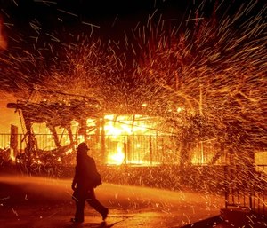 A firefighter passes a burning home as the Hillside fire burns in San Bernardino, Calif.