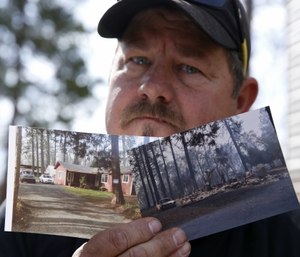 Bill Husa displays before-and-after photos of his home lost in last year's Camp Fire in Paradise, Calif. (AP Photo/Rich Pedroncelli)