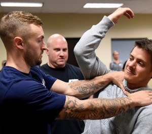 In this photo taken Sept. 10, 2019, Ryan Russo, left, and Mike Herrall go through a drill as instructor Sean Fuller looks on during a defensive tactic training class at the American Medical Response training center in Clackamas, Ore. Paramedics in Portland are undergoing mandatory training in defensive tactics after a rash of high-profile attacks against them as they respond to 911 calls for people in a mental health or drug-related crisis. (AP Photo/Steve Dykes)