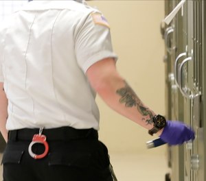 An officer with the GEO Group, Inc., uses an electronic device to log his visual inspections of cells.