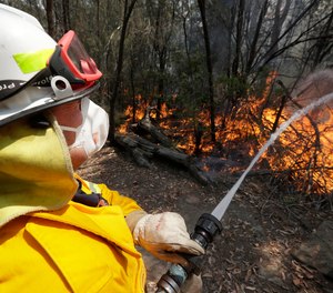 In this Dec. 8, 2019, photo a firefighter controls a backburn near Mangrove Mountain, north of Sydney, Australia. U.S. officials said Tuesday, Jan. 7, 2020, they are planning to send at least 100 more firefighters to Australia to join 159 already there battling blazes that have killed multiple people and destroyed thousands of homes.