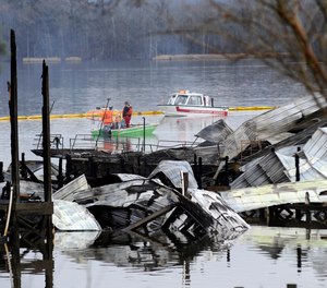 People on boats patrol near the charred remains of a dock following a fatal fire at a Tennessee River marina in Scottsboro, Ala., Monday, Jan. 27, 2020. Authorities said the explosive fire was reported overnight while people were sleeping on boats tied up at the structure.