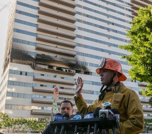 Los Angele Fire Department PIO Capt. Erik Scott, right, briefs the media on a fire that broke out at a 25-story high-rise apartment building, which started on a sixth-floor balcony and sent choking smoke billowing through the upper levels in West Los Angeles Wednesday, Jan. 29, 2020. (AP Photo/Damian Dovarganes)
