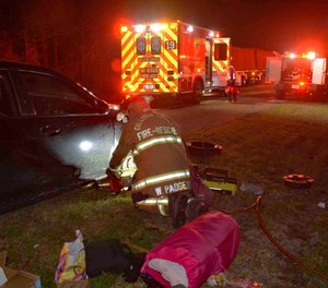 This photo provided by Colleton County Fire Rescue shows a member of the Colleton County, N.C., Fire-Rescue uses a tool to lift a woman’s car Sunday, Feb. 2, 2020. The woman called 911 with her toes after her hands were crushed while changing a flat tire. (Photo/Colleton County Fire Rescue via AP)