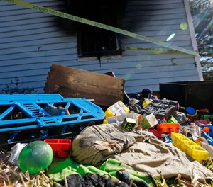 Burned children's clothing, furnishings exterior of a house at the scene of a fatal fire on Saturday, Feb. 8, 2020 in Clinton, Miss.