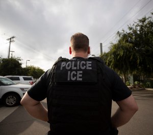In this July 8, 2019, file photo, a U.S. Immigration and Customs Enforcement (ICE) officer looks on during an operation in Escondido, Calif.
