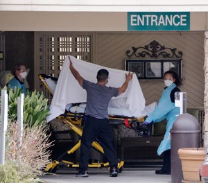A person is taken by stretcher to a waiting ambulance from a nursing facility where more than 50 people are sick and being tested for the COVID-19 virus, Saturday, Feb. 29, 2020, in Kirkland, Wash.