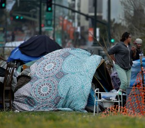 People are seen in a homeless encampment in Oakland, Calif. California Gov. Gavin Newsom has authorized $150 million in emergency funding to protect homeless people in California from the spread of COVID-19.