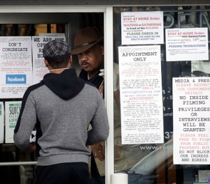 An employee answers questions at the entrance to a gun shop Tuesday, March 24, 2020, in Culver City, Calif. (AP Photo/Marcio Jose Sanchez)
