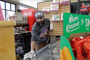 Mike Johnston, a clerk at the Maupin Market in tiny Maupin, Oregon, wipes down the ice cream case to protect customers from the new coronavirus. Image: AP Photo/Gillian Flaccus