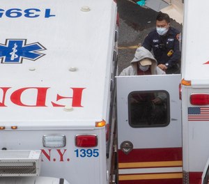 A paramedic transports a patient into the Trauma Center at the Elmhurst Hospital Center, Sunday, March 29, 2020, in the Queens borough of New York. FDNY EMS will be ordered not to transport cardiac arrest patients to the hospital if they cannot be resuscitated in the field, under a new rule made in response to overstretched hospital and ambulance resources due to COVID-19.