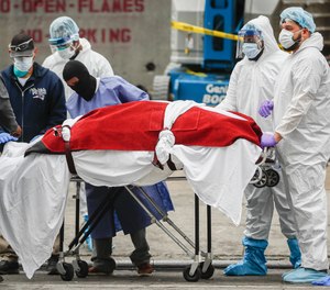 Healthcare personnel transport a deceased patient to a hearse at Brooklyn Hospital Center in Brooklyn borough of New York.