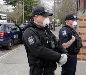Seattle Police officers wear N95 masks as they listen to conversation during a citizen call Thursday, April 2, 2020, in Seattle.