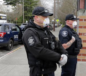 Seattle Police officers wear N95 masks as they listen to conversation during a citizen call Thursday, April 2, 2020, in Seattle.