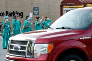 Piedmont Athens Regional Medical Center health care professionals stand and wave from the sidewalk at the Caravan of Care as it parades around the hospital in Athens, Ga., Sunday, April 5, 2020. The Caravan was organized to show support for the community's health care professionals who are battling the coronavirus pandemic. Image: Joshua L. Jones/Athens Banner-Herald via AP
