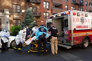 FDNY EMS providers wearing personal protective equipment move a patient into an ambulance on April 14, 2020.