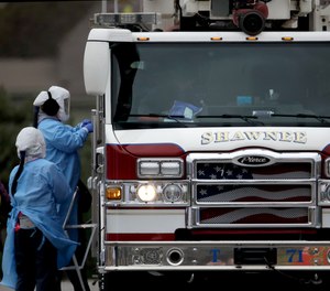 Healthcare workers test a firefighter for COVID-19 at a drive-in testing center in Shawnee, Kan. A proposed Kansas bill would provide hourly hazard pay of $3 per hour for eligible essential workers, including first responders and healthcare workers.