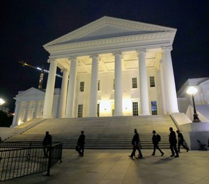 House of Delegates members walk past the south portico at the Virginia State Capitol in Richmond, Va., Wednesday, April 22, 2020.