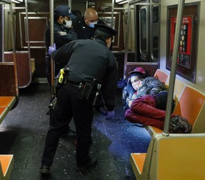 NYPD and MTA officers wake up a sleeping passenger on a subway train in Manhattan on Thursday, April 30, 2020.