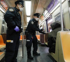 NYPD officers wake up sleeping passengers and direct them to the exits, Thursday, April 30, 2020, in Manhattan.