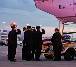 Ambulnz paramedics and Aurora firefighters salute as the casket carrying the body of paramedic Paul Cary is removed from a plane at Denver International Airport on Sunday, May 3, 2020, in Denver. Cary died from coronavirus after volunteering to help combat the pandemic in New York City.