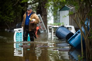 Mark Musselman brings a chair to the front of his house from the back yard, wading through floodwater, Tuesday, May 19, 2020 in Edenville, Mich. Image: Katy Kildee/Midland Daily News via AP