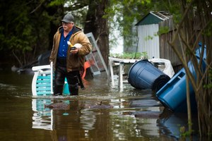 Mark Musselman brings a chair to the front of his house from the back yard, wading through floodwater, Tuesday, May 19, 2020 in Edenville, Mich. Image: Katy Kildee/Midland Daily News via AP
