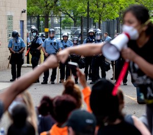 People gather in front of Minneapolis police officers Wednesday, May 27, 2020, as they protest the arrest and death of George Floyd. (Carlos Gonzalez/Star Tribune via AP)