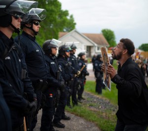 A demonstrator stands in front of police officers outside the home of fired Minneapolis police Officer Derek Chauvin on Wednesday evening, May 27, 2020. (Jeff Wheeler/Star Tribune via AP)