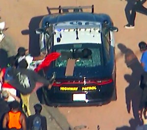 Protesters attack a CHP cruiser during a Black Lives Matter protest on a freeway in downtown Los Angeles on Wednesday, May 27, 2020. Hundreds of people protesting the death of a black man in Minneapolis police custody blocked the freeway.
