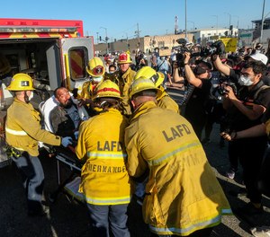Los Angeles firefighters transfer a demonstrator to an ambulance during a protest.