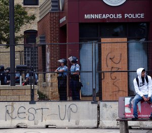 Police officers guard the Minneapolis Police Third Precinct, Thursday, May 28, 2020, after a night of rioting.