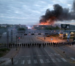 Law enforcement officers amassed along Lake Street near Hiawatha Ave. as fires burned after a night of unrest and protests in the death of George Floyd early Friday, May 29, 2020 in Minneapolis.