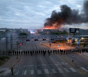 Law enforcement officers amassed along Lake Street near Hiawatha Ave. as fires burned after a night of unrest and protests in the death of George Floyd early Friday, May 29, 2020 in Minneapolis.