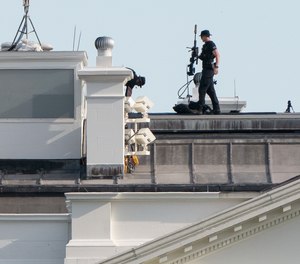 A U.S. Secret Service counter-sniper team looks out from atop the White House.