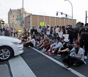 Protesters sit at an intersection during a protest over the deaths of George Floyd and Breonna Taylor, Saturday, May 30, 2020, in Louisville, Ky.